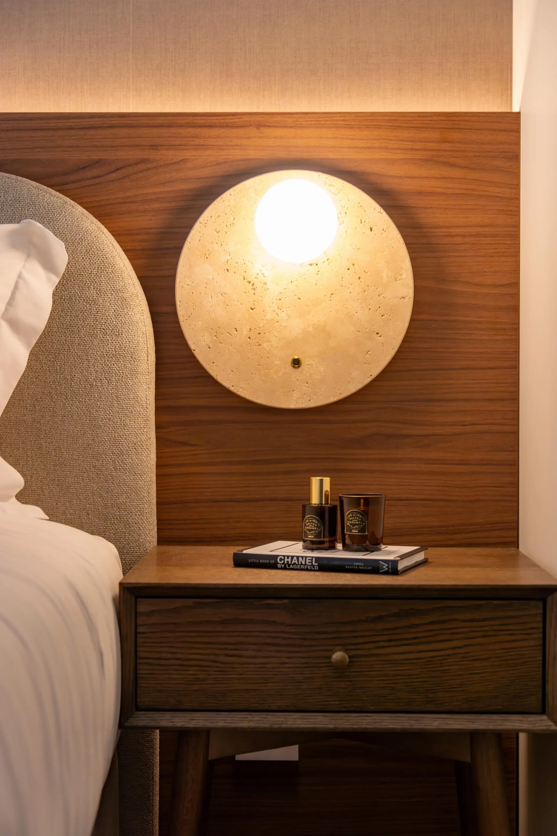 Nattbord med tent duftlys, bok og nordisk designlampe i kveldsstemning