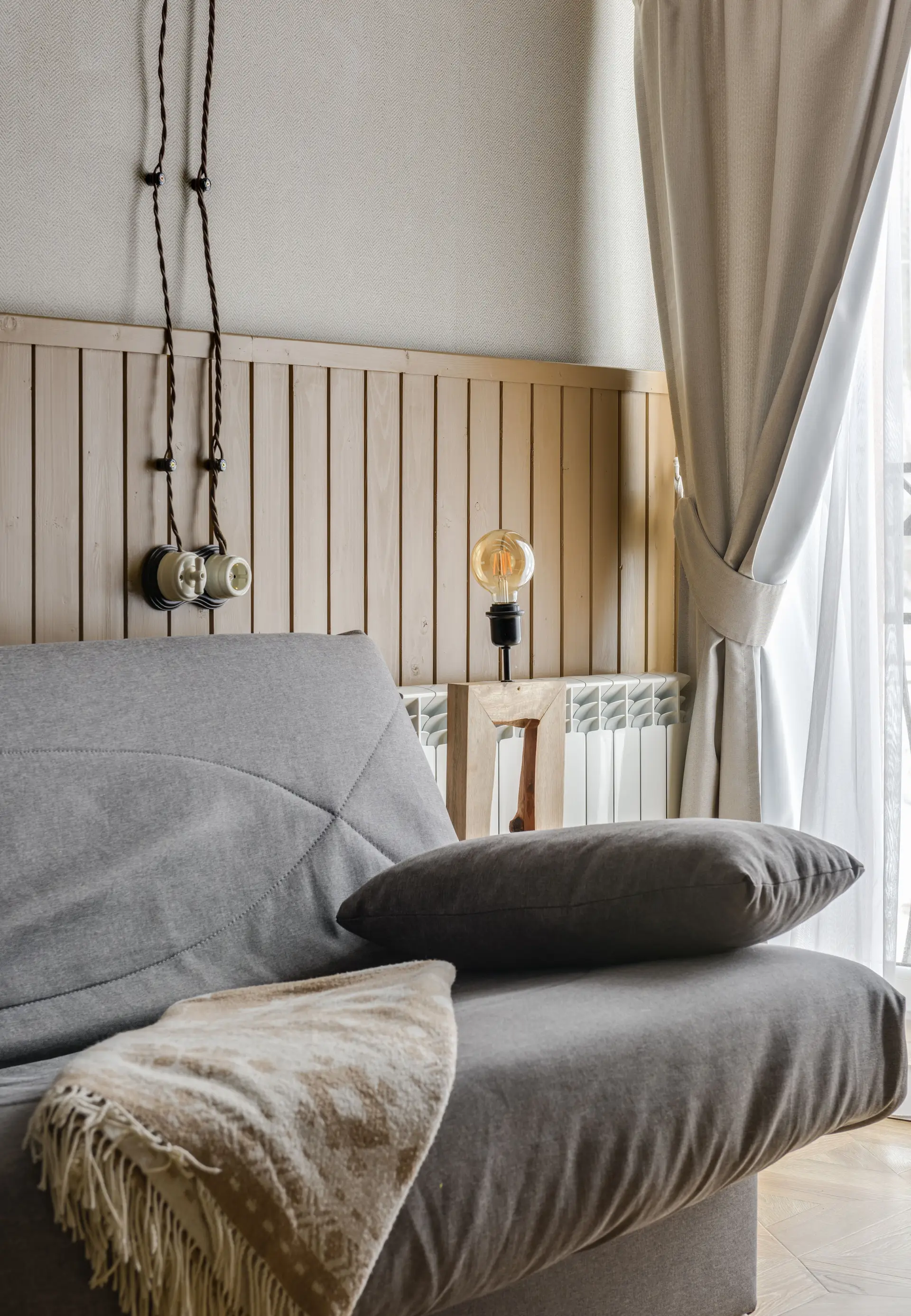 Lunt oppholdsrom med sofa i naturlige tekstiler og dagslys gjennom lin-gardiner